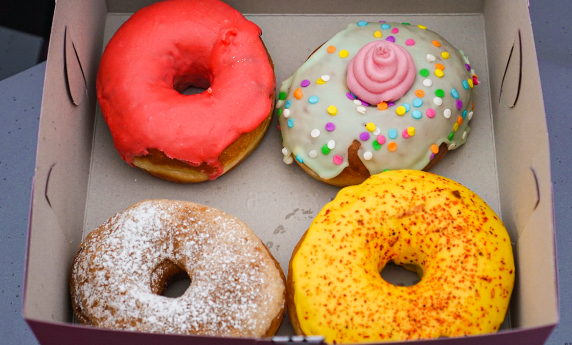 4 colorful vegan donuts in a box