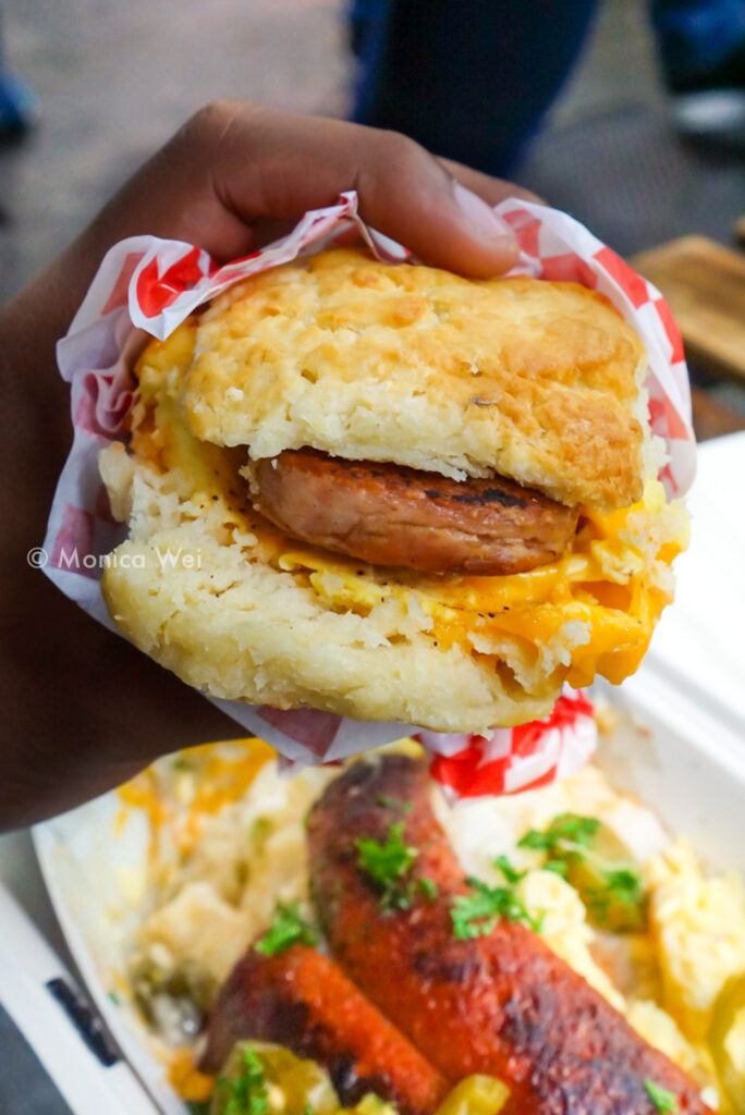 sausage biscuit sandwich being held over hot links biscuits and gravy