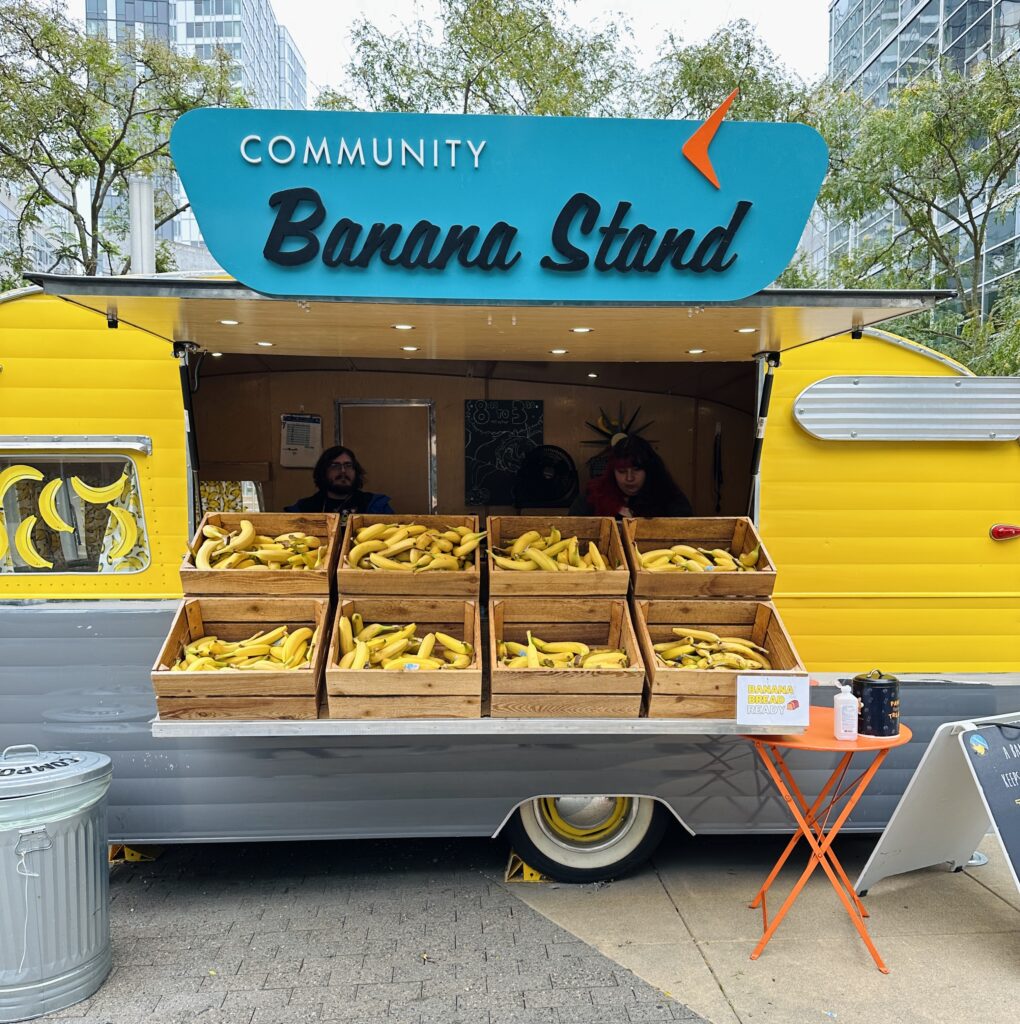 yellow trailer with sign that says community banana stand, with boxes of bananas