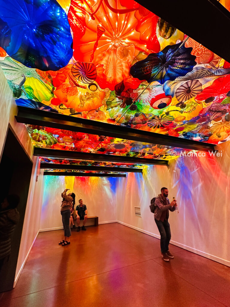 colorful glass sculptures on the ceiling reflect down light in art gallery